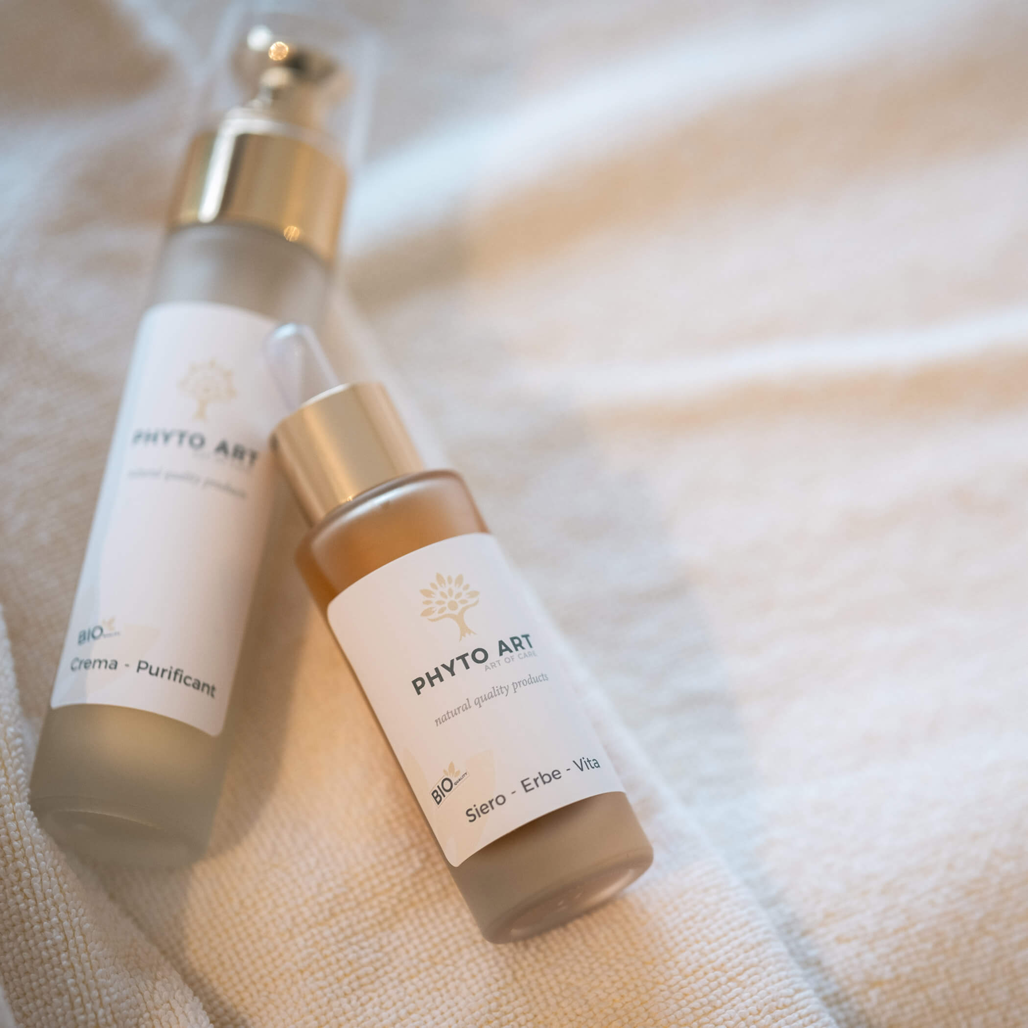 Zwei Phyto Art-Pflegeflaschen auf einem weichen beigen Handtuch, eine aufrecht und eine liegend. - Hotel La Casies Mountain Living
