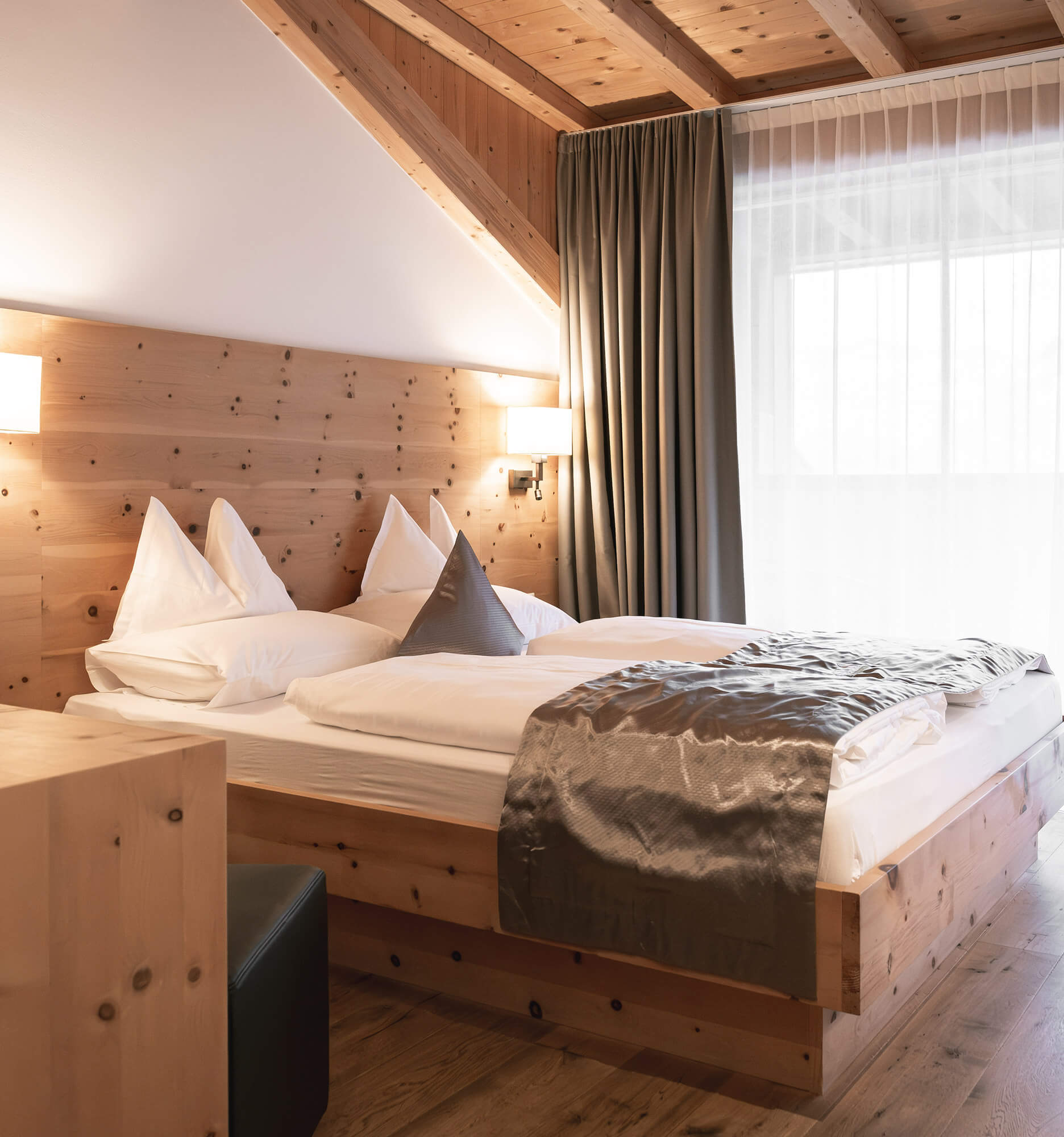 Gemütliches Hotelzimmer mit Holzausstattung, Doppelbett, sanfter Beleuchtung und großem Fenster mit Vorhängen. - Hotel La Casies Mountain Living