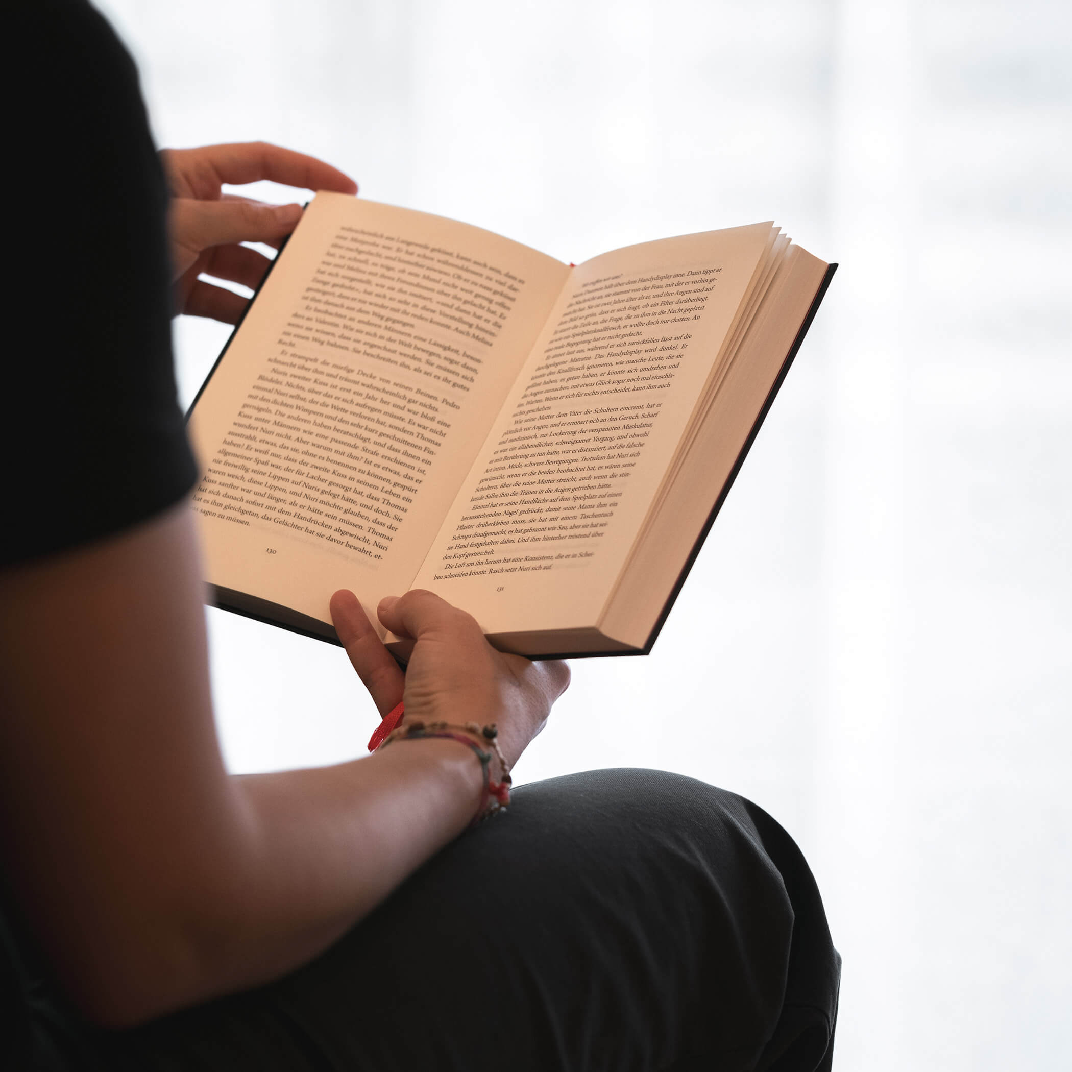 Sitzende Person, die ein aufgeschlagenes Buch liest, wobei der Text auf den Seiten sichtbar ist. - Hotel La Casies Mountain Living