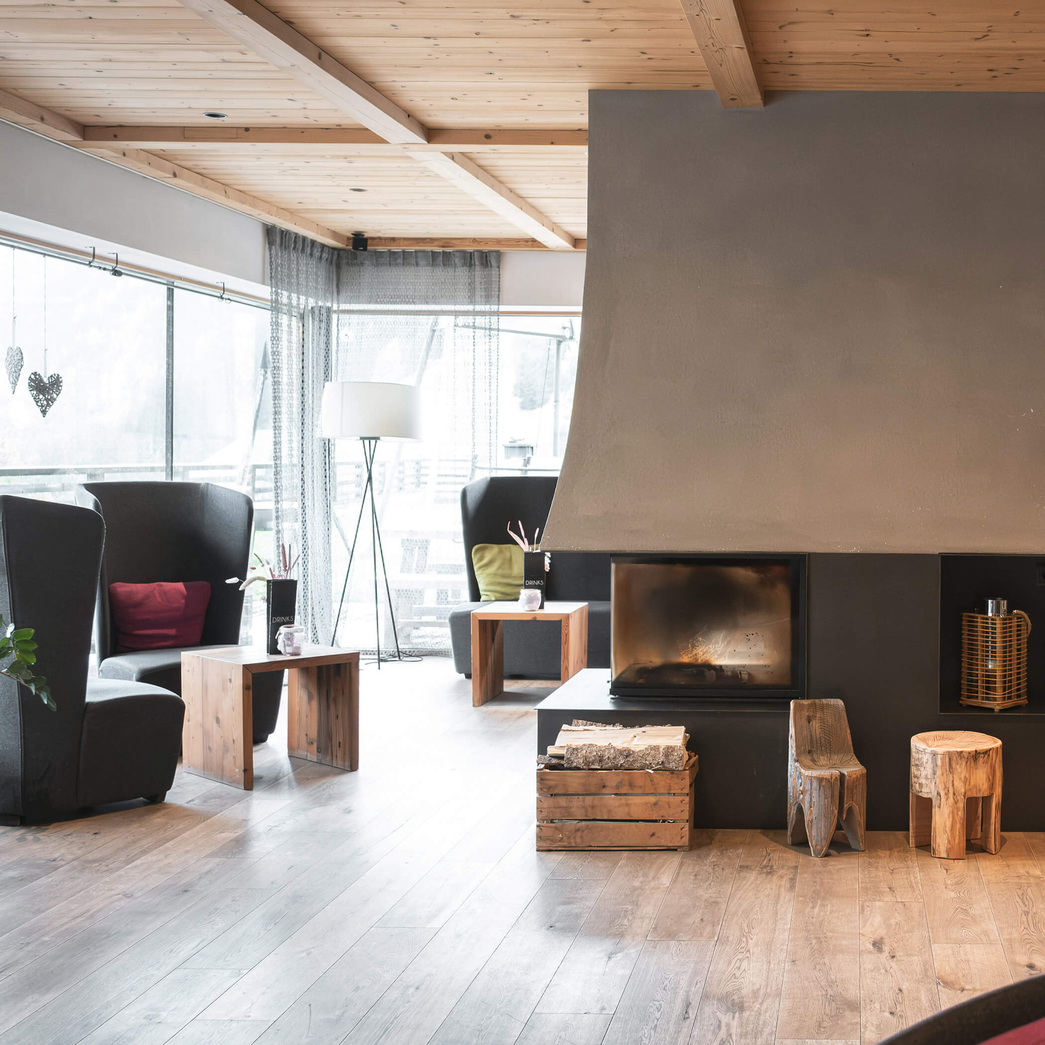 Modernes, gemütliches Wohnzimmer mit Kamin, Holzmöbeln, großen Fenstern und natürlichem Licht. - Hotel La Casies Mountain Living