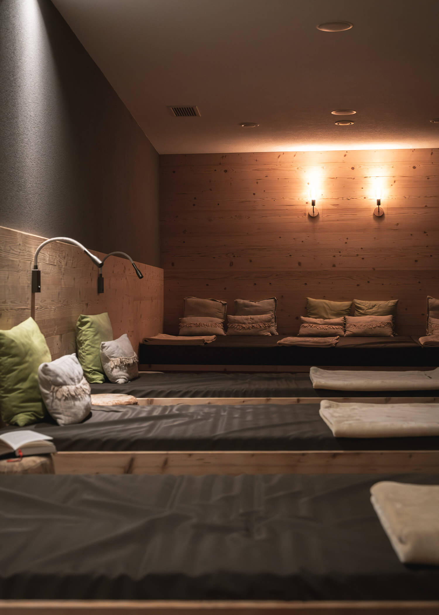 Dimly lit spa lounge with cushioned loungers, pillows, and soft wall lighting creating a relaxing atmosphere. - Hotel La Casies Mountain Living
