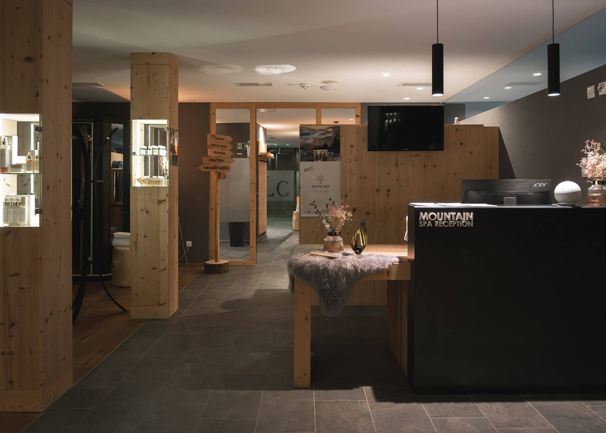 Empfangsbereich eines modernen Bergspas mit Holzdekor, schummriger Beleuchtung und schwarzem Empfangstresen. - Hotel La Casies Mountain Living