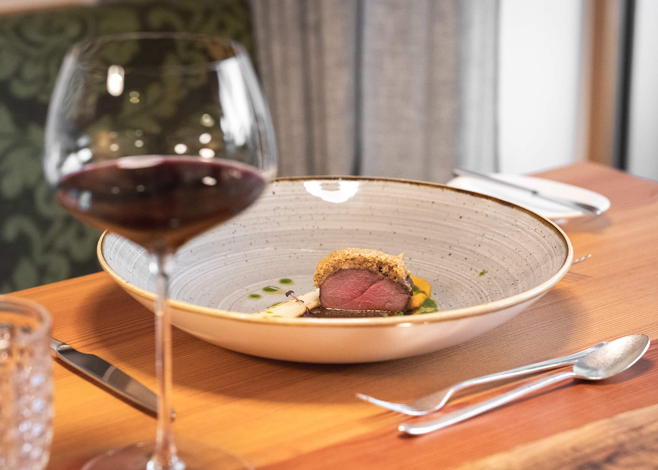 Ein Teller mit Essen und ein Glas Wein. - Hotel La Casies Mountain Living