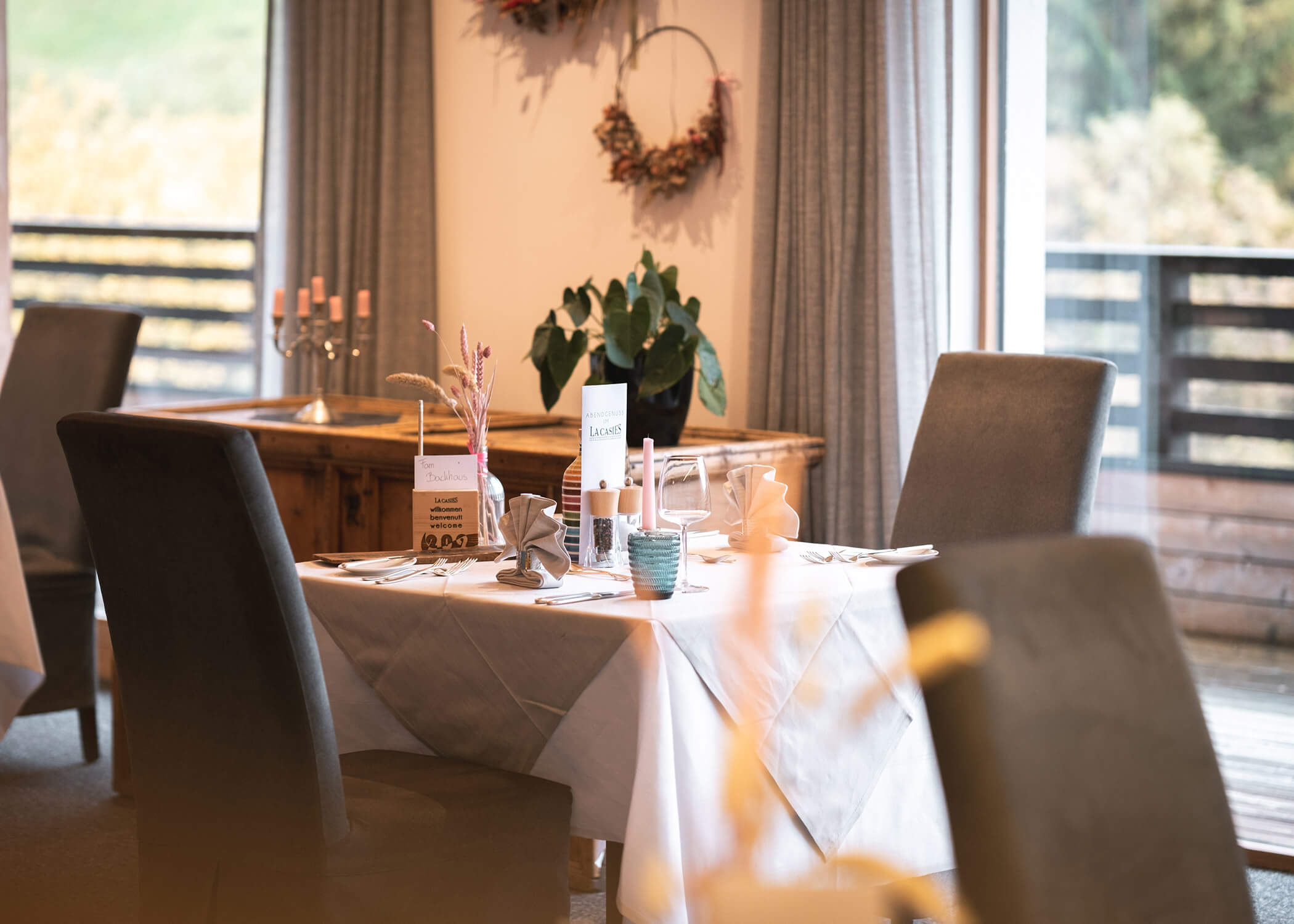 Eleganter Restauranttisch mit Speisekarten, Gläsern und Servietten vor großen Fenstern mit Tageslicht. - Hotel La Casies Mountain Living