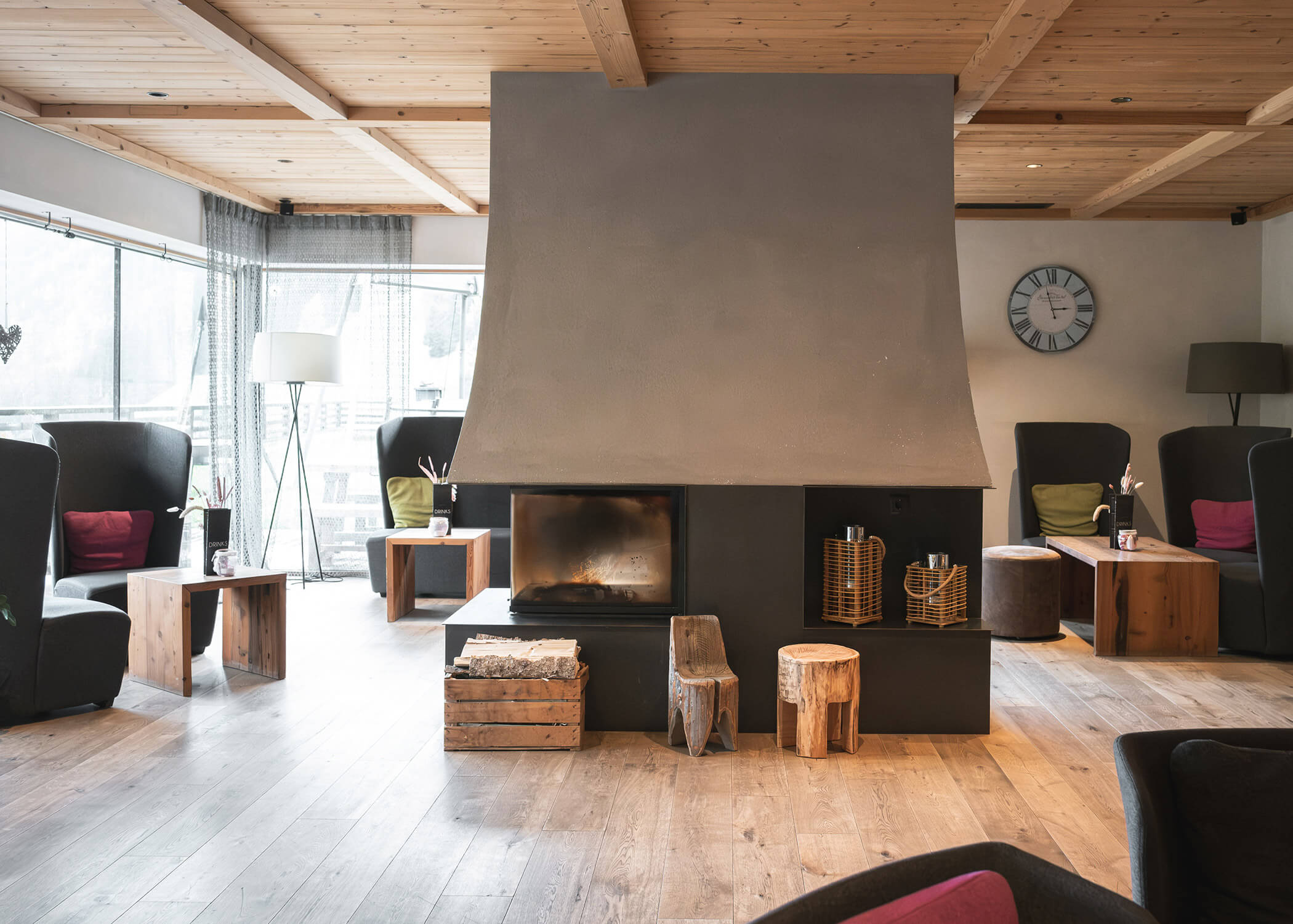 Moderne Lounge mit zentralem Kamin, Holzmöbeln, großen Fenstern und gemütlichen Sesseln. - Hotel La Casies Mountain Living