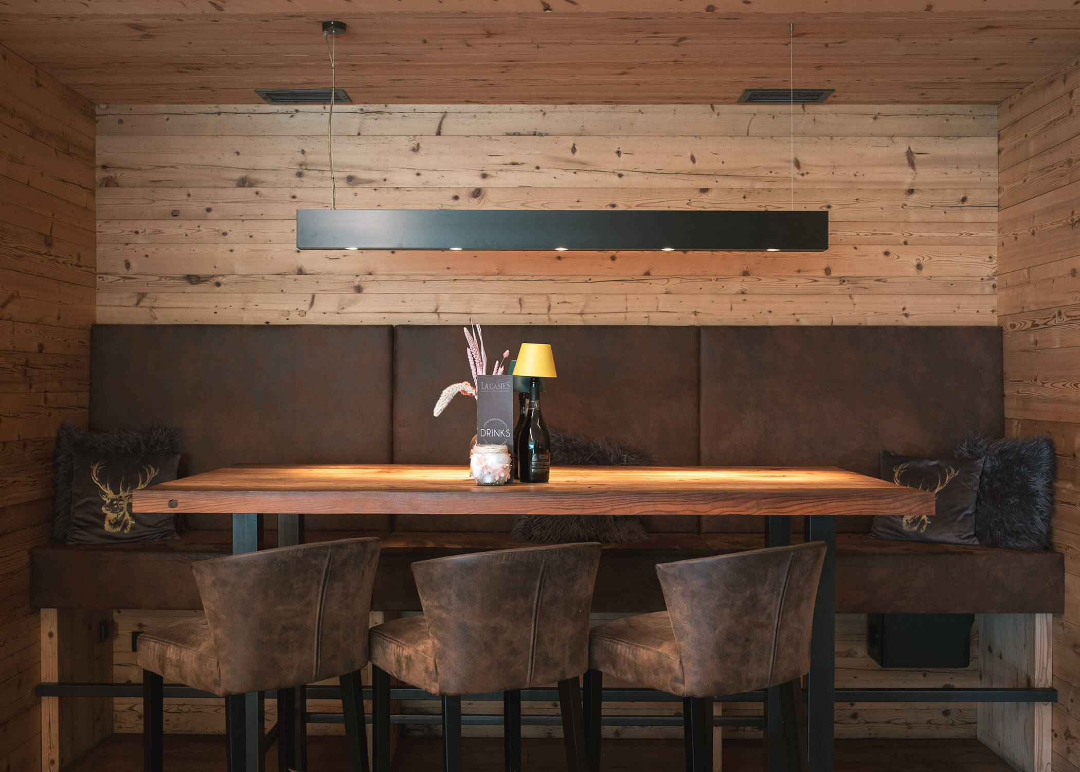 Ein rustikaler Essbereich mit einem Holztisch, braunen Lederstühlen und gemütlichen, holzgetäfelten Wänden. - Hotel La Casies Mountain Living