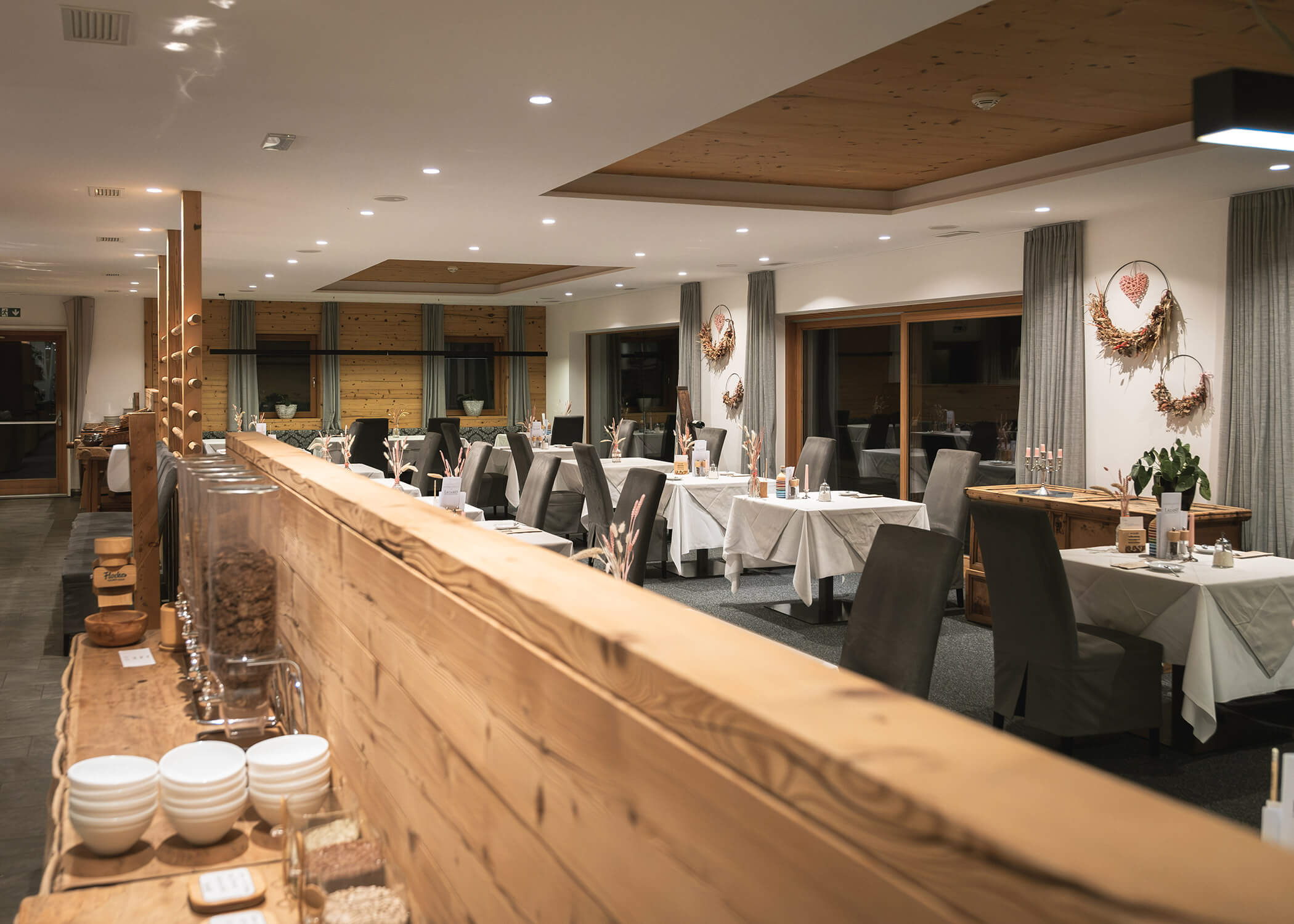 Modernes Restaurant mit sauber gedeckten Tischen, grauen Stühlen, Holzakzenten und Frühstücksbuffet. - Hotel La Casies Mountain Living