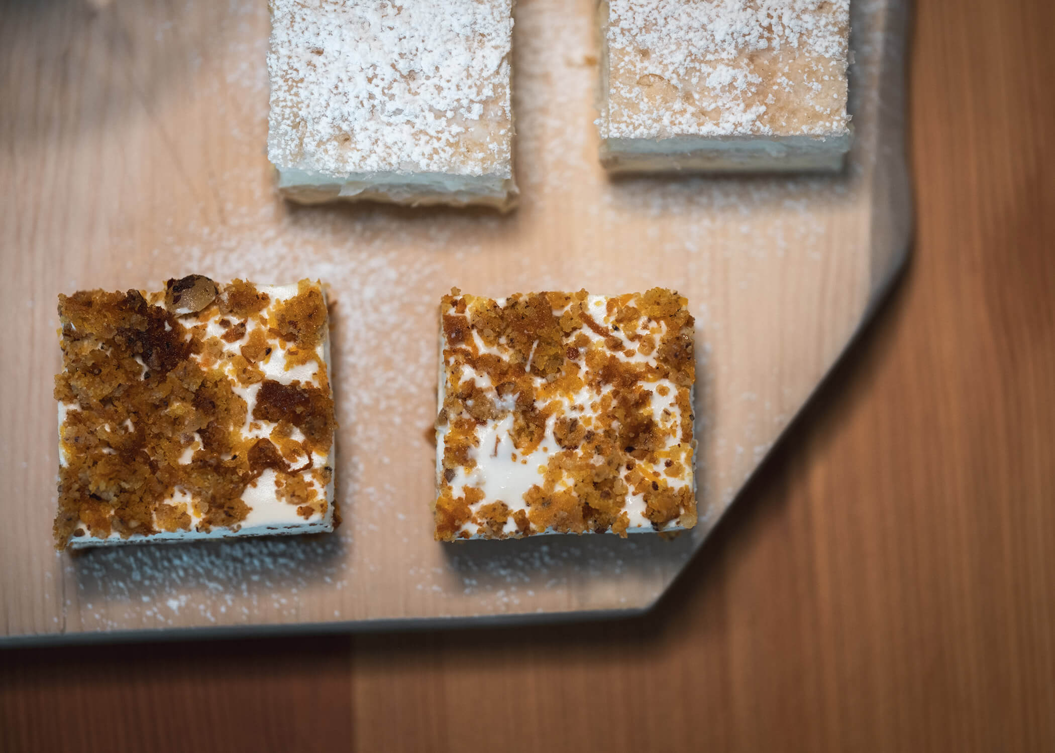 Eine Gruppe von quadratischen Desserts auf einer Holzfläche. - Hotel La Casies Mountain Living