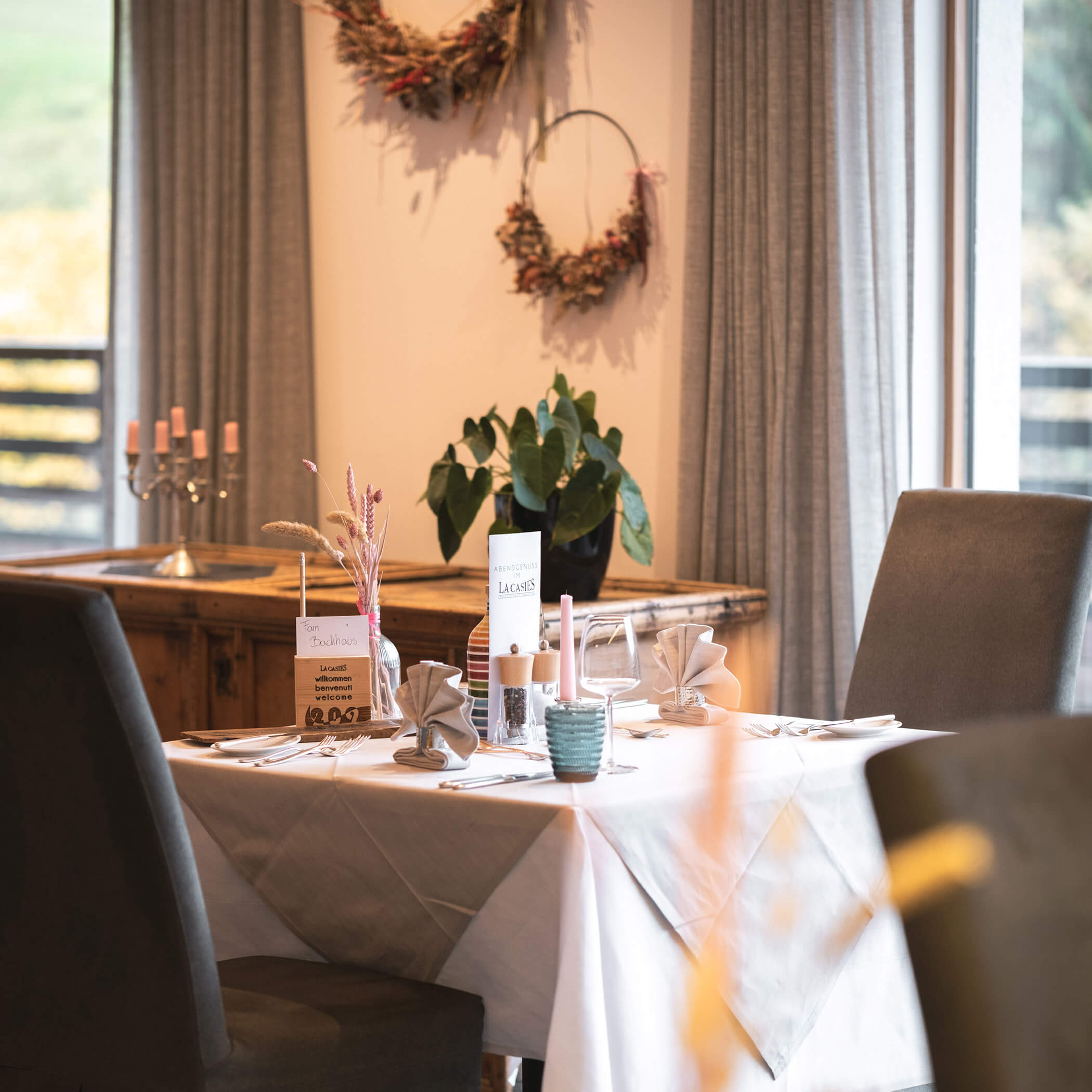 Eleganter Restauranttisch für zwei Personen mit gefalteten Servietten, Speisekarten und sanftem Tageslicht am Fenster. - Hotel La Casies Mountain Living