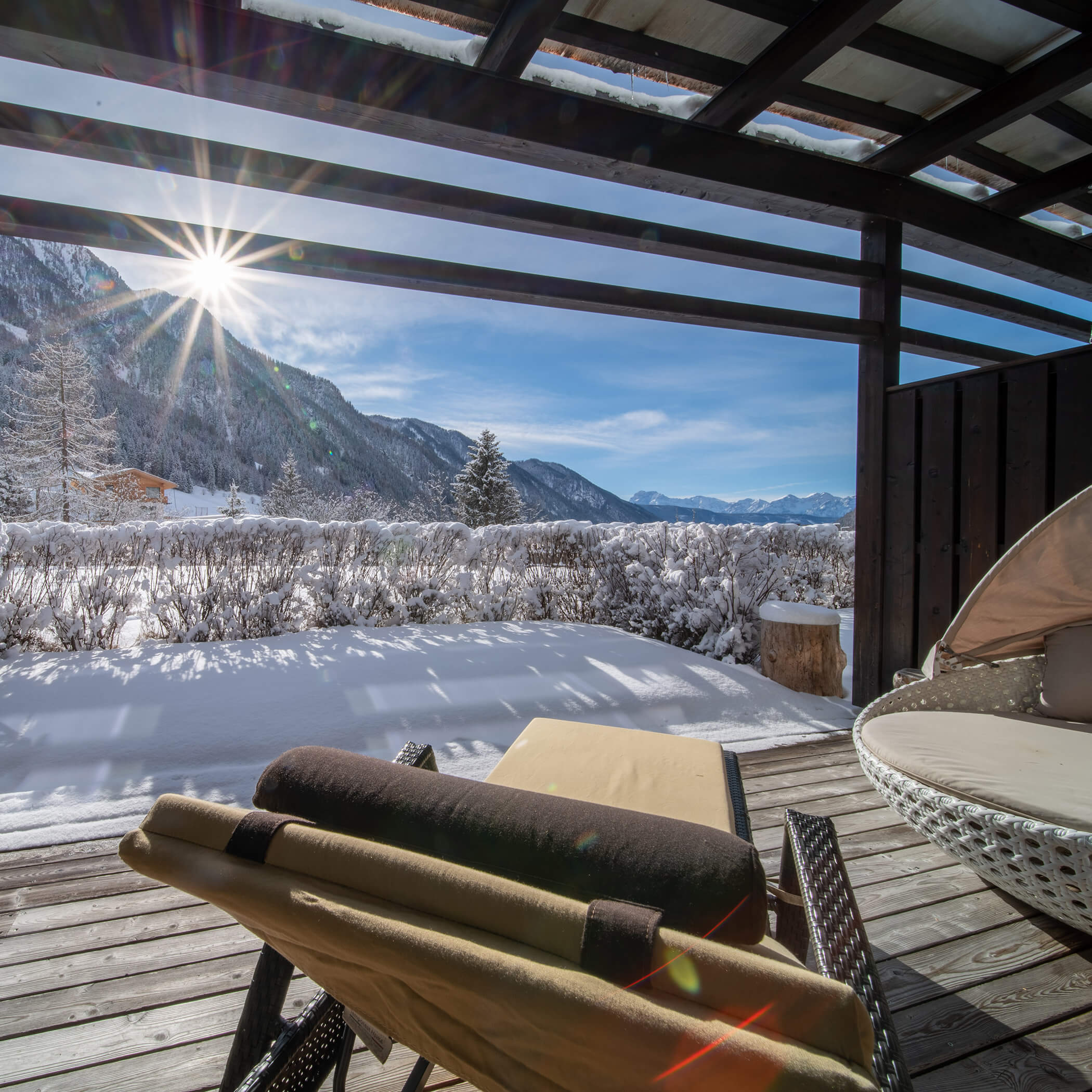 Zwei Liegestühle auf einer verschneiten Terrasse bieten einen Blick auf die Berge unter einem strahlenden, sonnigen Winterhimmel. - Hotel La Casies Mountain Living