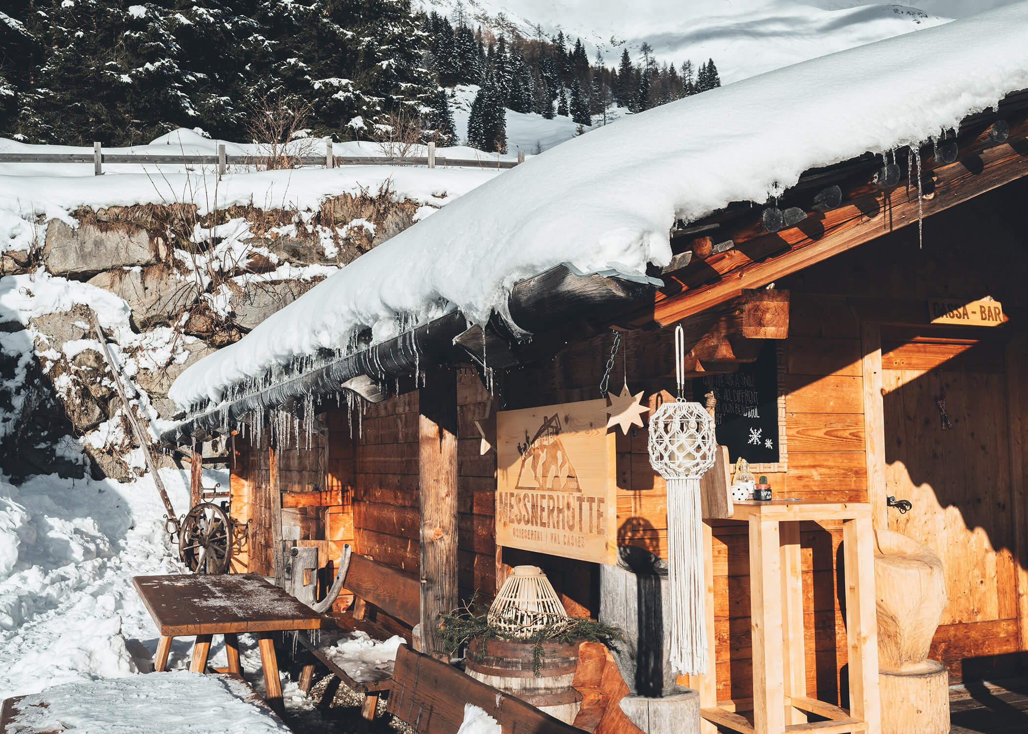 Eine hölzerne, verschneite Berghütte mit Eiszapfen am Dach in einer Winterlandschaft. - Hotel La Casies Mountain Living