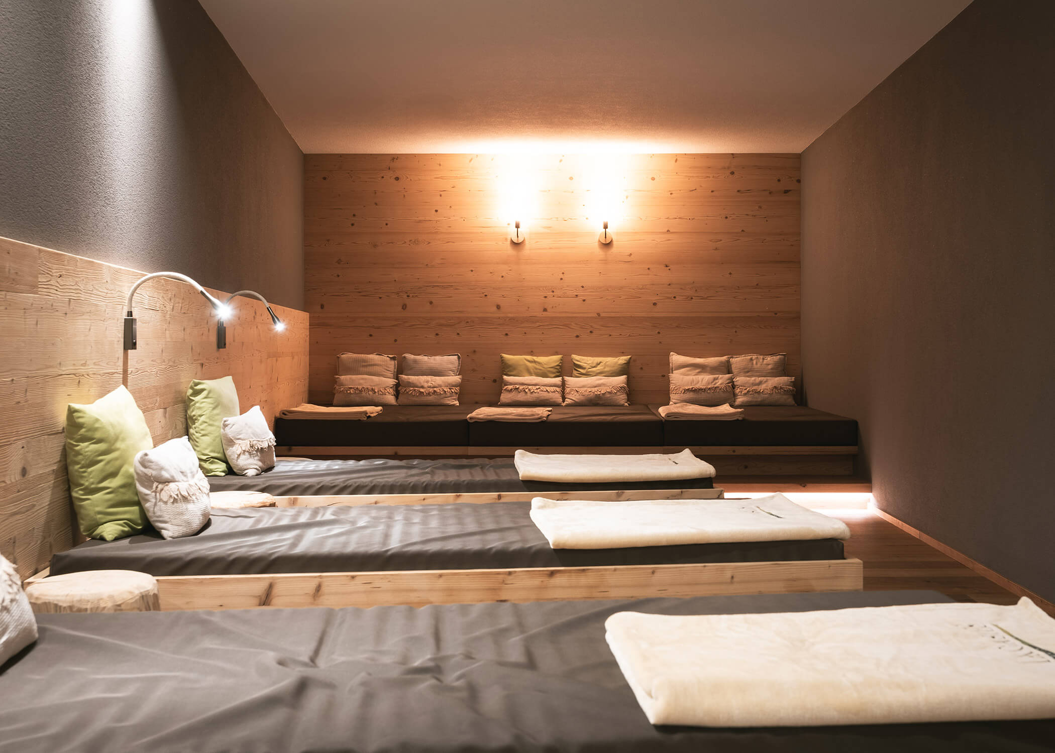 Ein ruhiger Spa-Ruheraum mit Holzwänden, Lounge-Betten, sanfter Beleuchtung und gemütlichen Kissen. - Hotel La Casies Mountain Living