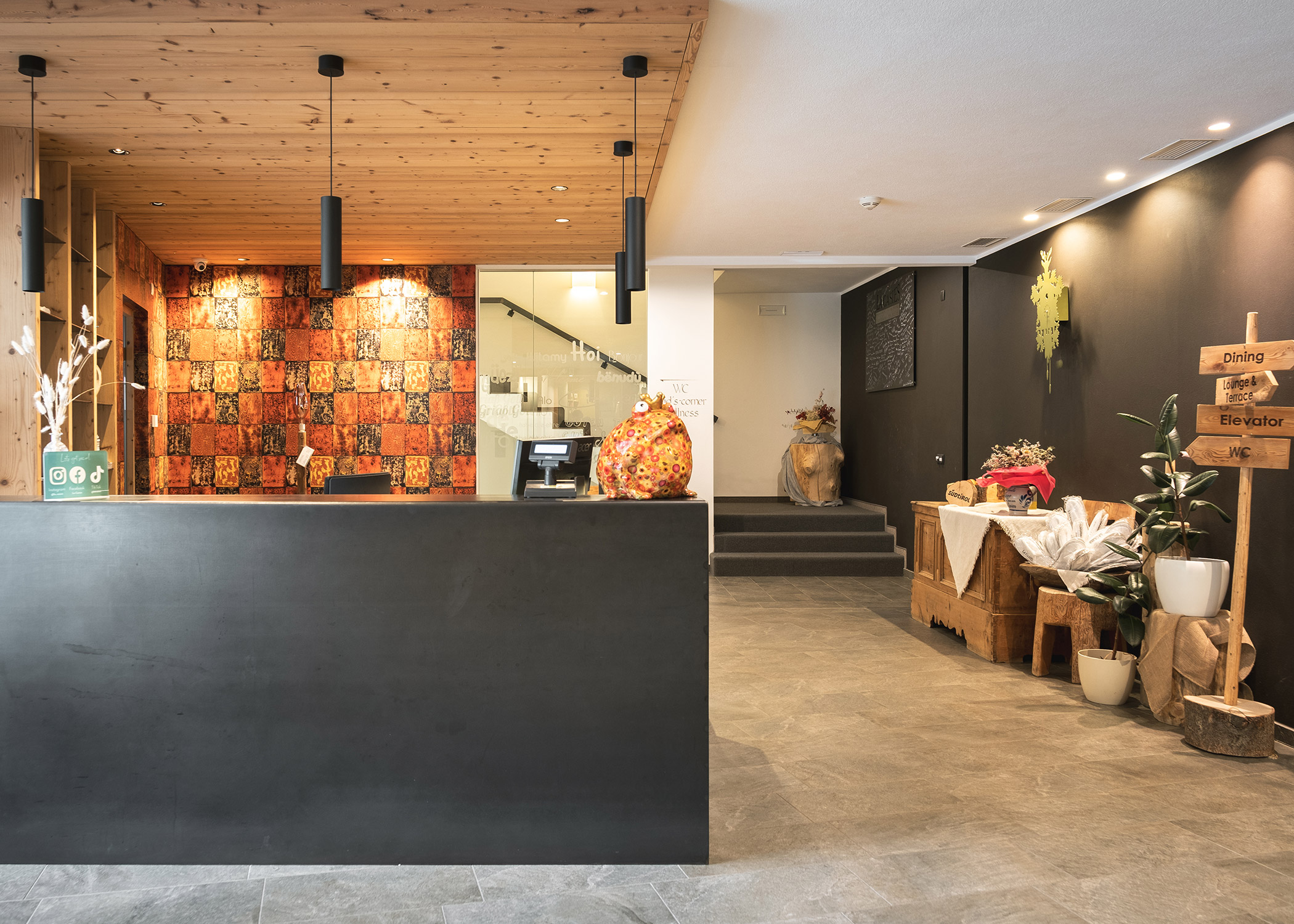 Moderner Hotelempfangsbereich mit dunkler Rezeption, Holzdekor und einladenden Sitzgelegenheiten. - Hotel La Casies Mountain Living