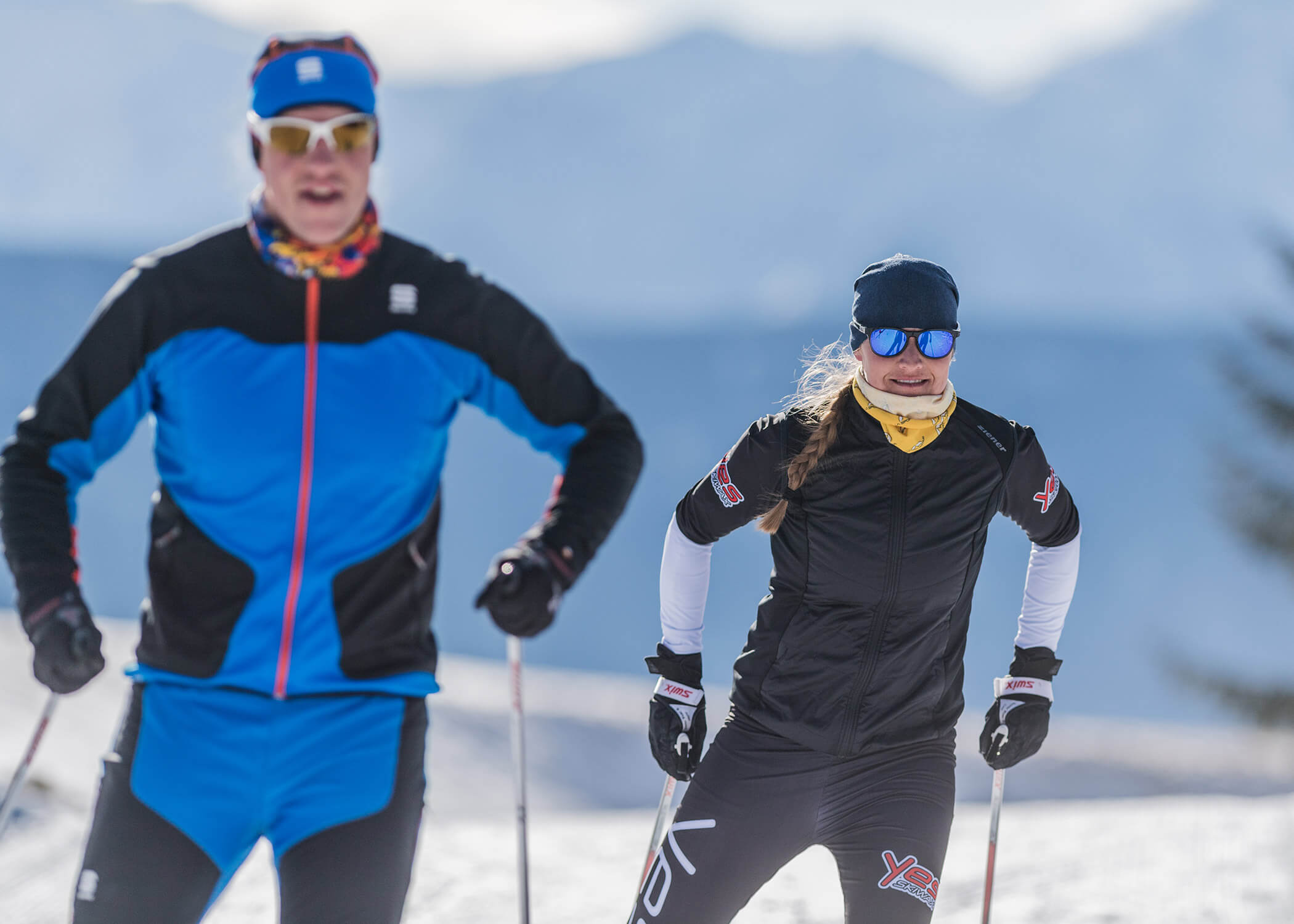 Zwei Personen beim Skilanglauf auf Schnee mit Bergen im Hintergrund an einem sonnigen Tag. - Hotel La Casies Mountain Living
