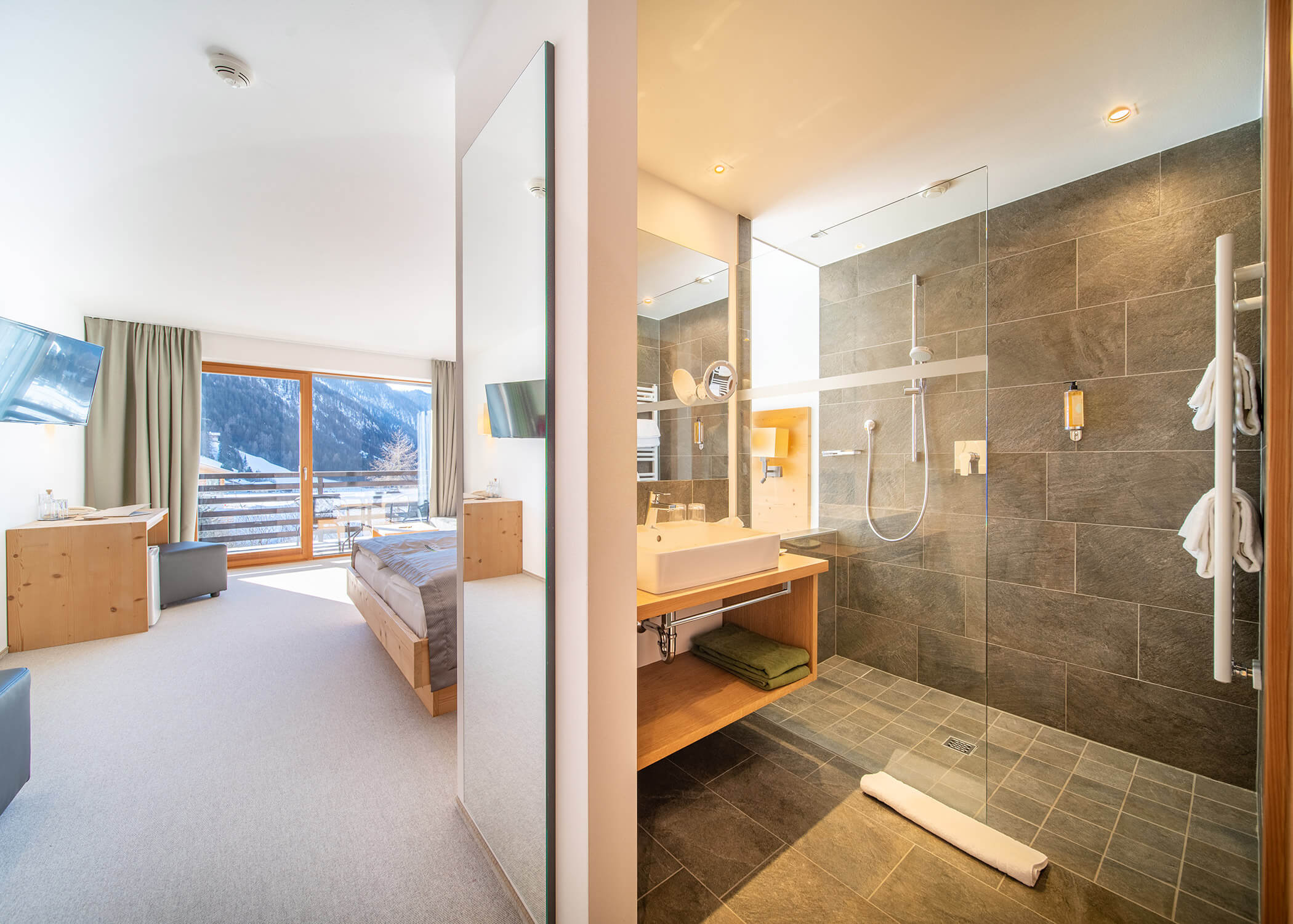 Modernes Hotelzimmer mit Bergblick, separatem Bad mit Glaswänden und Holzmöbeln. - Hotel La Casies Mountain Living