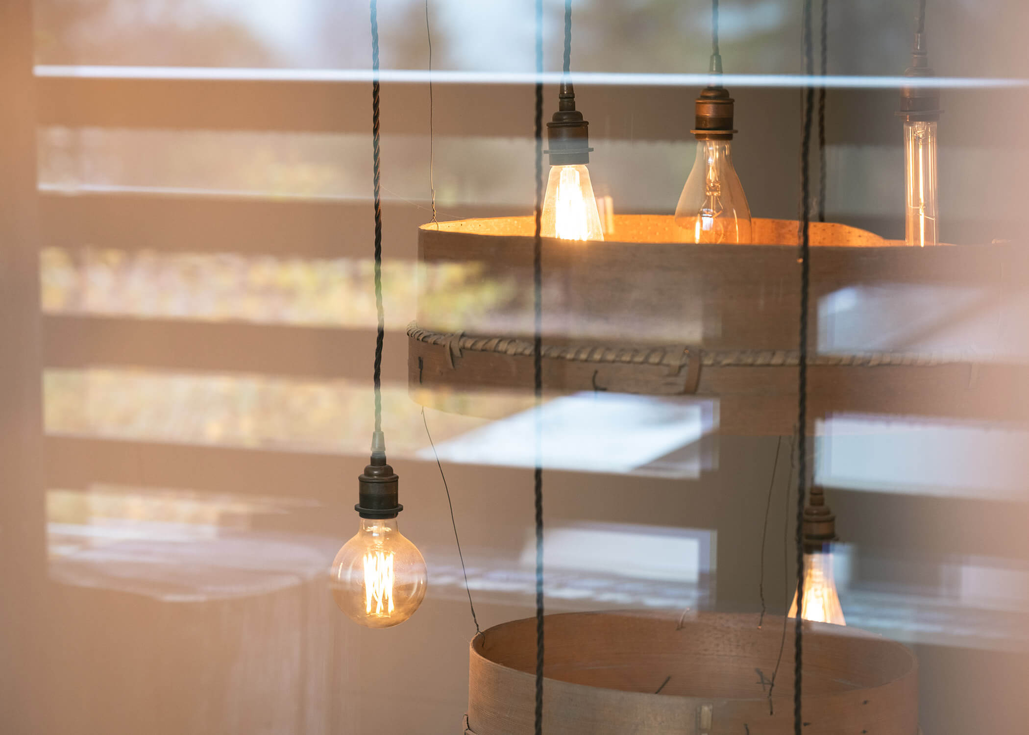 Nahaufnahme von freiliegenden hängenden Glühbirnen, die sich in einem Fenster spiegeln, mit einem unscharfen Hintergrund im Freien. - Hotel La Casies Mountain Living