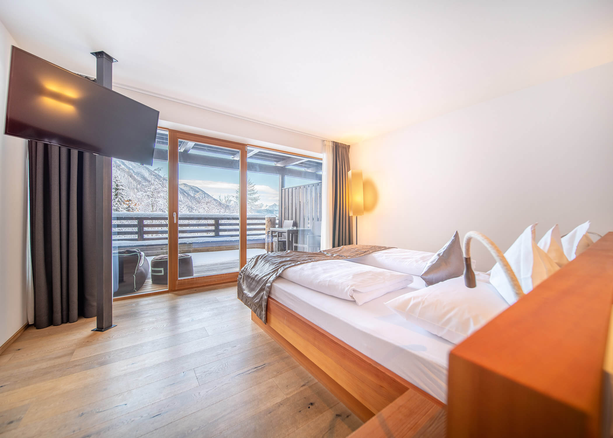 Modernes Hotelzimmer mit großem Bett, TV und Balkon mit Blick auf verschneite Berge. - Hotel La Casies Mountain Living