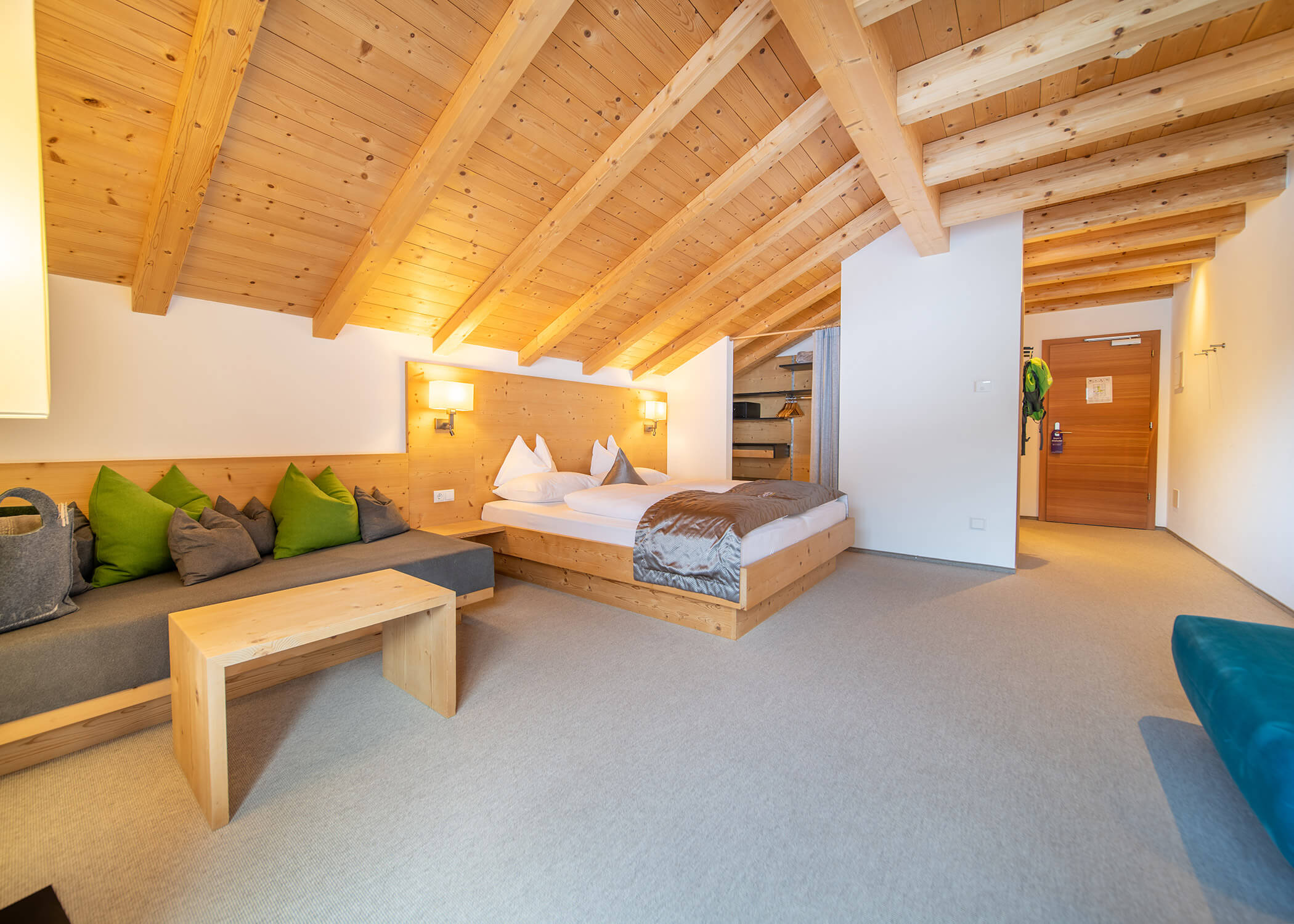 Gemütliches Hotelzimmer mit Holzdecke, Doppelbett, Sofa, Couchtisch und sanfter Beleuchtung. - Hotel La Casies Mountain Living