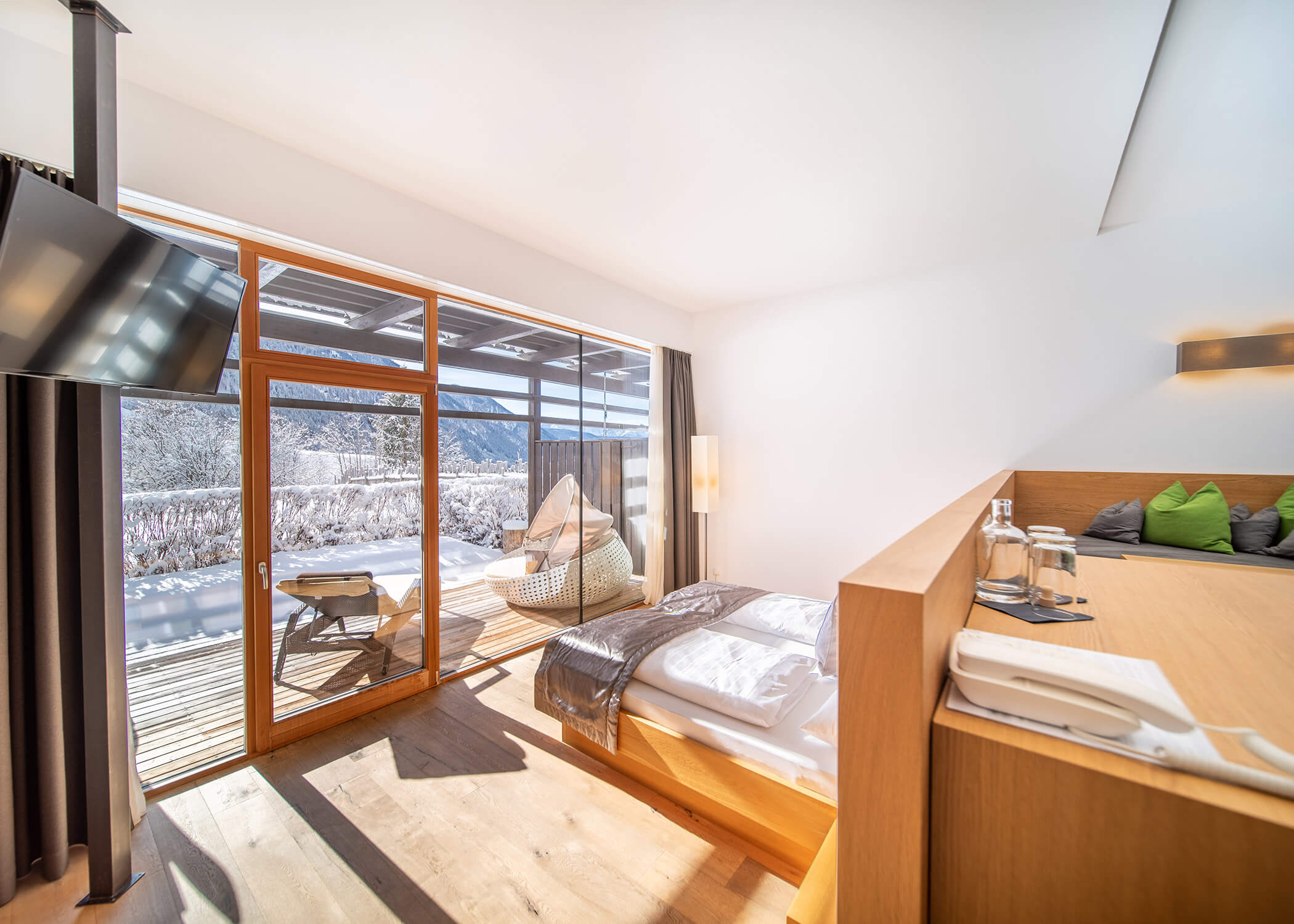 Modernes Schlafzimmer mit großen Glastüren, die auf einen verschneiten Balkon mit Liegestühlen und Bergblick führen. - Hotel La Casies Mountain Living