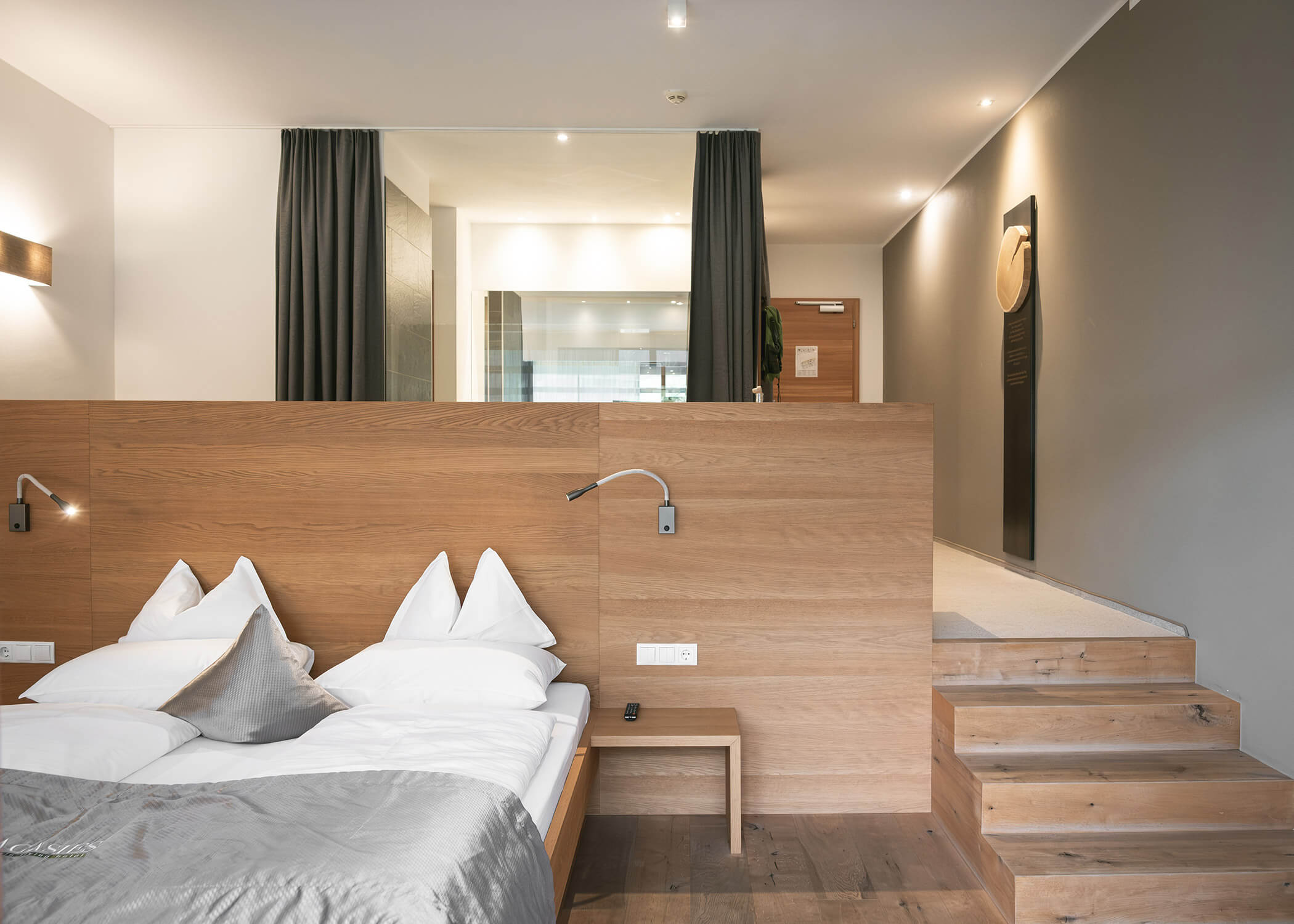 Modernes Hotelzimmer mit Doppelbett, Holztrennwand, Treppe und neutraler Farbgestaltung. - Hotel La Casies Mountain Living