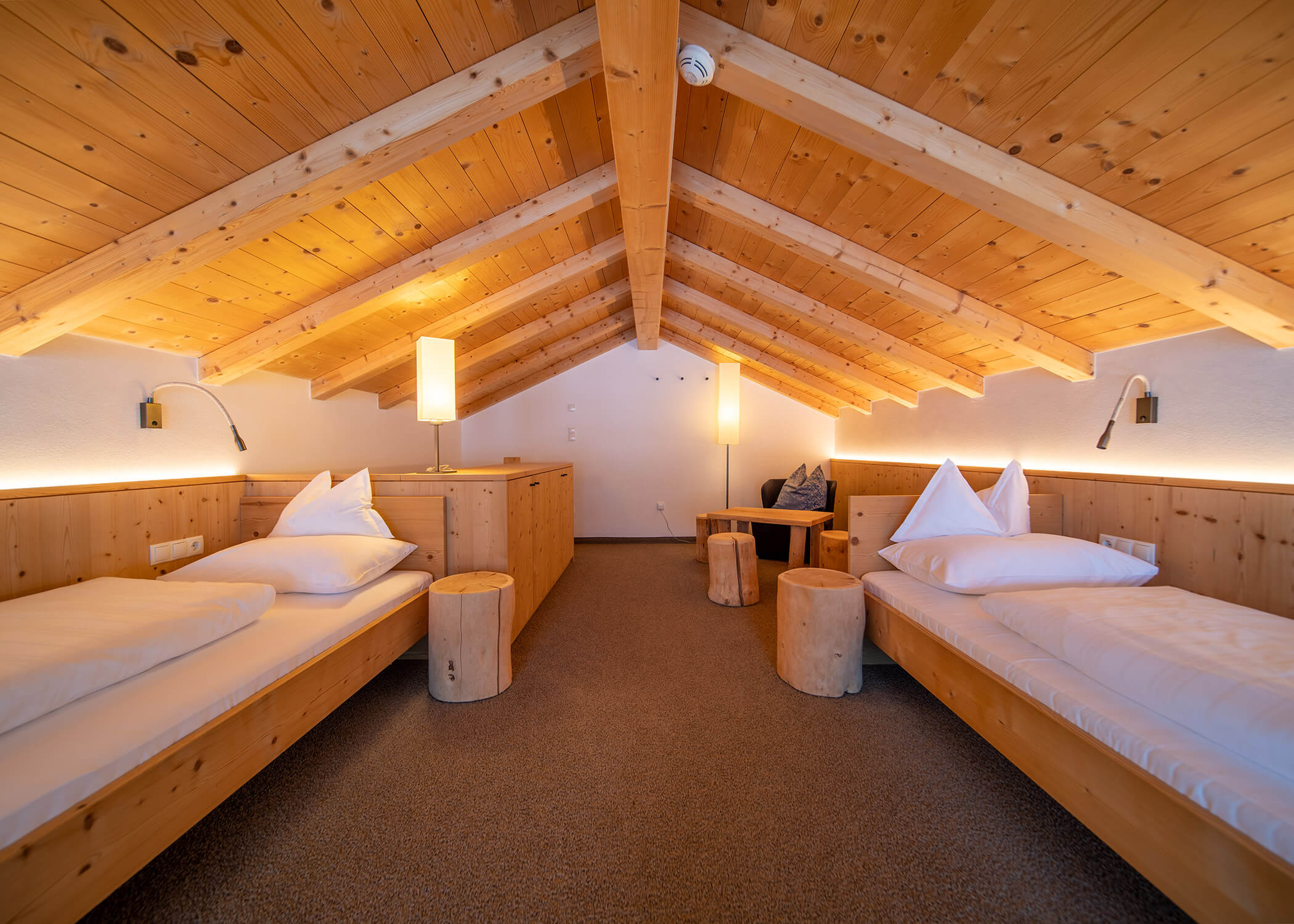 Gemütliches Zimmer im Dachgeschoss mit zwei Einzelbetten, Holzdecke und warmer Raumbeleuchtung. - Hotel La Casies Mountain Living